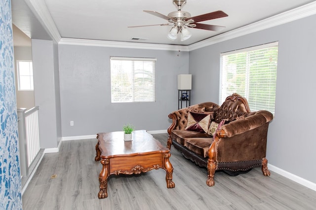 living area with ornamental molding, a ceiling fan, wood finished floors, and a wealth of natural light
