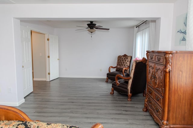 living area featuring baseboards, ceiling fan, and wood finished floors