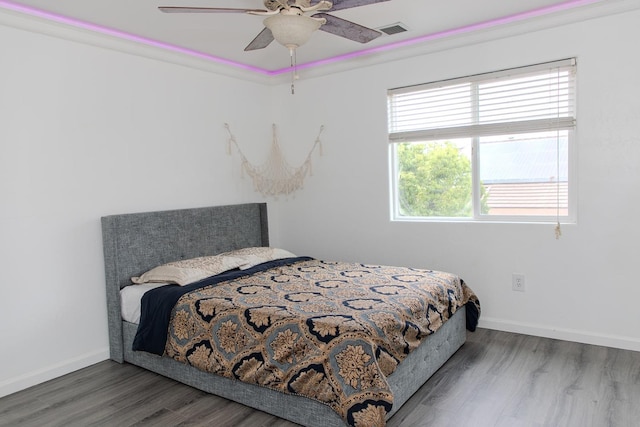 bedroom featuring baseboards, a ceiling fan, wood finished floors, and visible vents