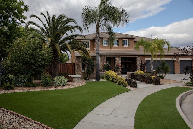 view of front of house featuring fence, driveway, a front lawn, and stone siding