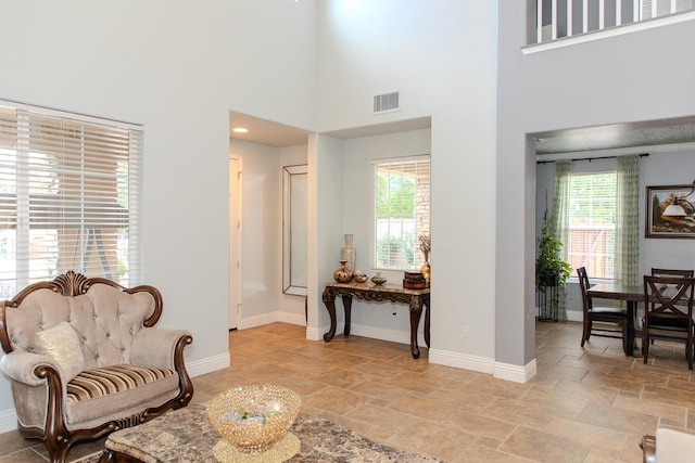 living area featuring stone finish flooring, visible vents, and plenty of natural light