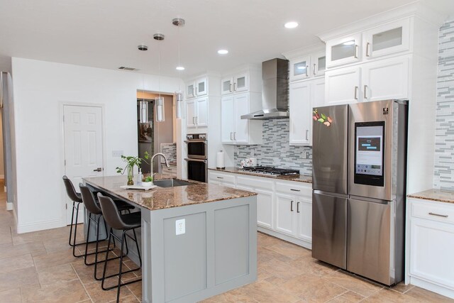 3107 Indianapolis Ave, Clovis, CA 93619 - kitchen with stainless steel appliances, wall chimney range hood, tasteful backsplash, an island with sink, and stone counters