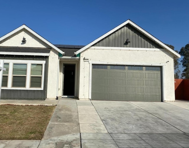 5244 W Fern Ave, Fresno, CA 93722 - ranch-style house with a garage, board and batten siding, stucco siding, roof mounted solar panels, and concrete driveway