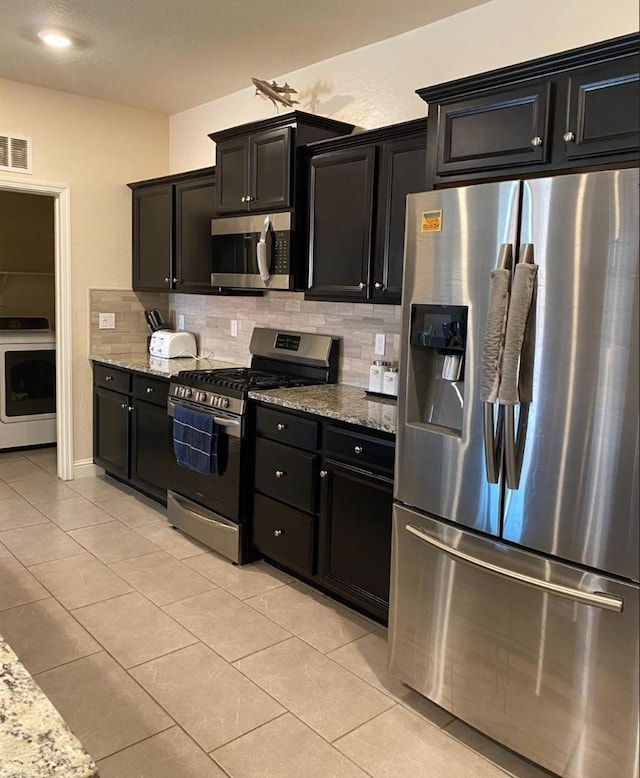 5244 W Fern Ave, Fresno, CA 93722 - kitchen featuring visible vents, decorative backsplash, washer / dryer, dark cabinets, and appliances with stainless steel finishes