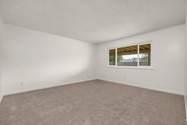 carpeted spare room with baseboards and a textured ceiling
