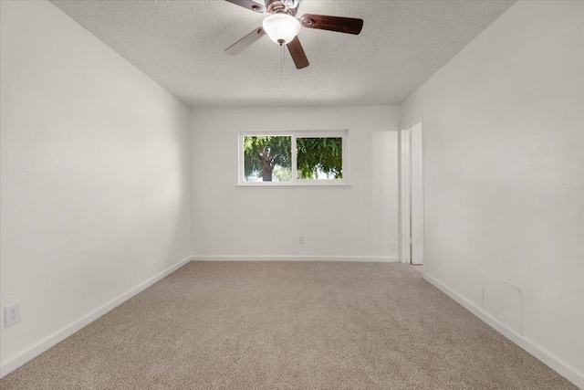 carpeted empty room with baseboards, ceiling fan, and a textured ceiling