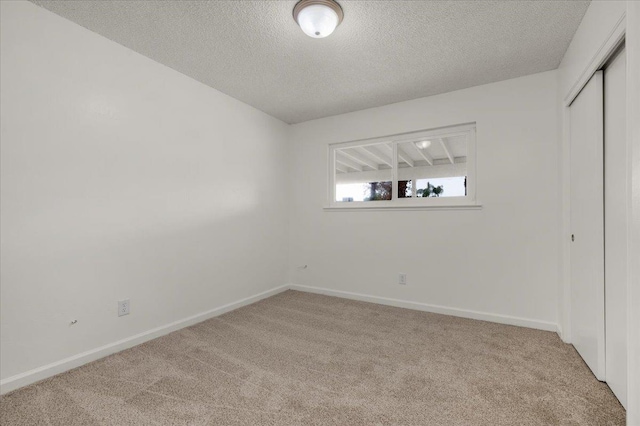 unfurnished bedroom with a textured ceiling, baseboards, carpet, and a closet