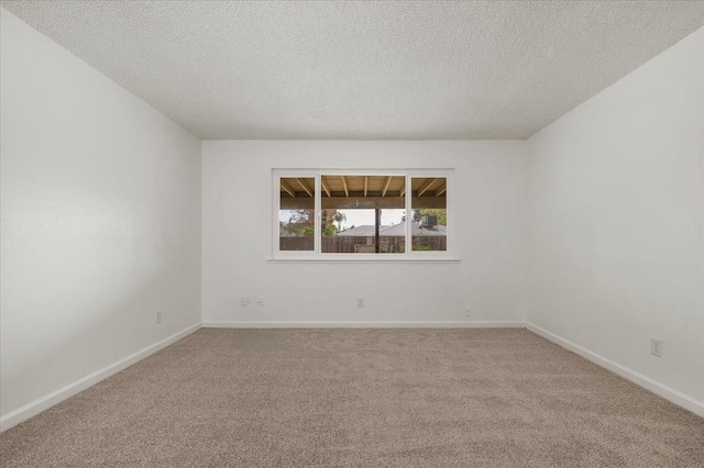 unfurnished room with carpet floors, a textured ceiling, and baseboards