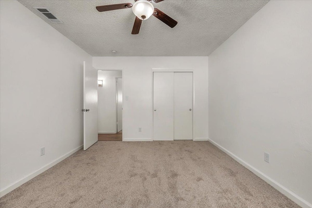 unfurnished bedroom with visible vents, carpet, a textured ceiling, and baseboards