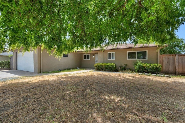 ranch-style home with concrete driveway, stucco siding, and fence