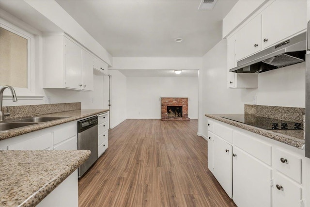 kitchen with a sink, visible vents, a brick fireplace, stainless steel dishwasher, and under cabinet range hood
