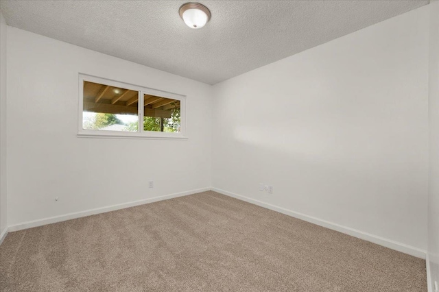 spare room featuring a textured ceiling, baseboards, and carpet