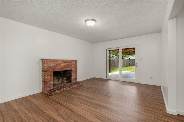 unfurnished living room featuring baseboards, a textured ceiling, wood finished floors, and a fireplace