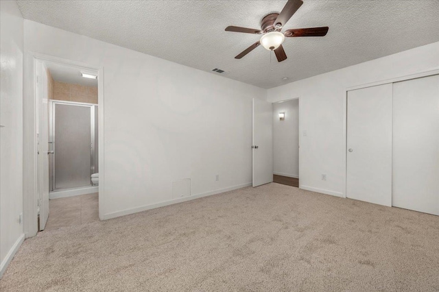 unfurnished bedroom with a closet, visible vents, a textured ceiling, carpet flooring, and ensuite bath