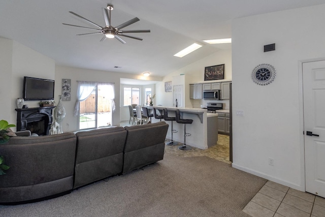 6577 E Kerckhoff Ave, Fresno, CA 93727 - living room featuring light tile patterned flooring, ceiling fan, light carpet, a fireplace, and lofted ceiling