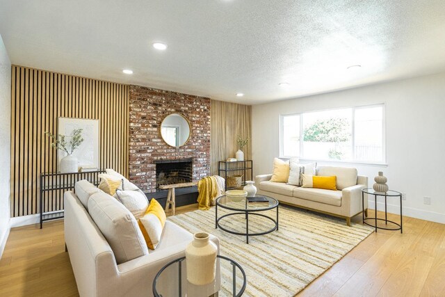living room with a brick fireplace, wood finished floors, baseboards, recessed lighting, and a textured ceiling