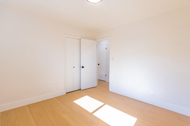 unfurnished bedroom with light wood-style floors, baseboards, and a closet