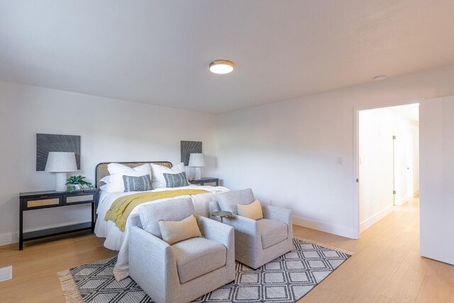 bedroom with baseboards, wood finished floors, and visible vents