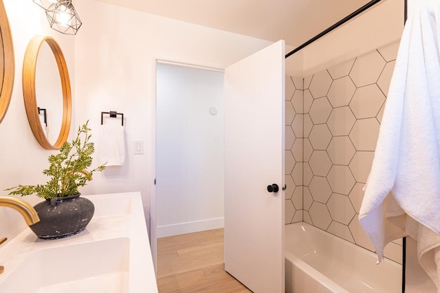 bathroom with double vanity, shower / tub combination, wood finished floors, a sink, and baseboards