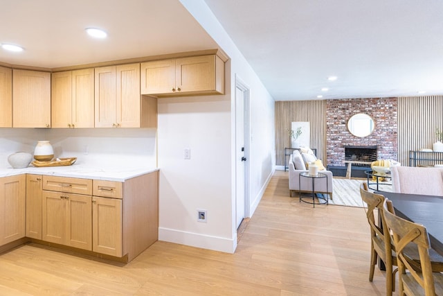 kitchen featuring baseboards, open floor plan, light wood-type flooring, and light brown cabinets