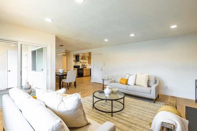 living room with recessed lighting, baseboards, and light wood-type flooring