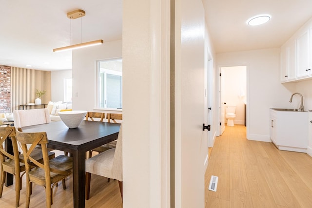 dining area featuring baseboards, light wood-style flooring, and visible vents