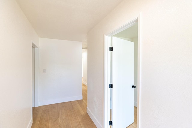 hall featuring baseboards and light wood finished floors