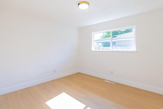 empty room with visible vents, light wood-style flooring, and baseboards