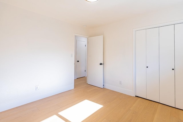 unfurnished bedroom with baseboards, a closet, and light wood-style flooring