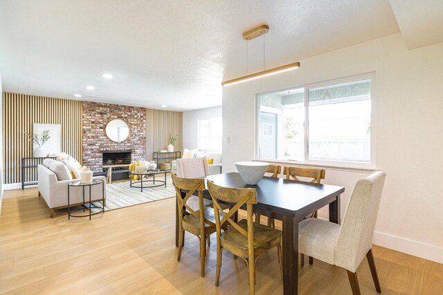dining room featuring recessed lighting, baseboards, light wood-type flooring, and a fireplace