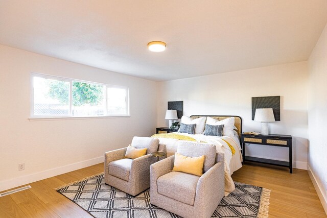 bedroom with baseboards, light wood-style flooring, and visible vents