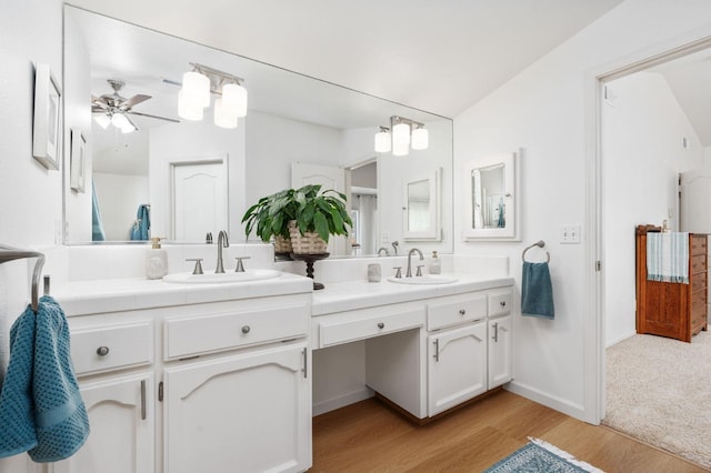 full bath with double vanity, a ceiling fan, a sink, and wood finished floors