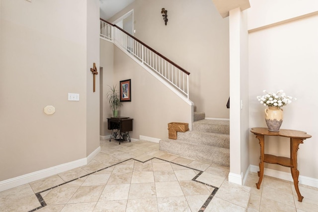 entrance foyer featuring baseboards, a high ceiling, light tile patterned flooring, and stairway