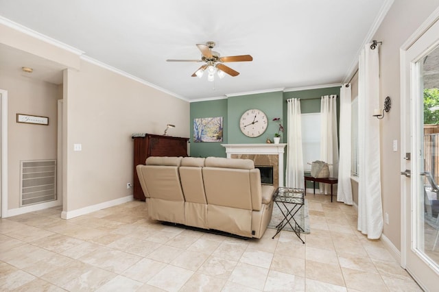 living area featuring a ceiling fan, a tile fireplace, light tile patterned floors, baseboards, and ornamental molding