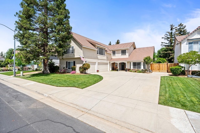 view of front of house with concrete driveway, an attached garage, fence, and a front yard