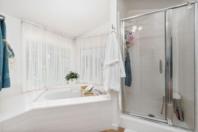 bathroom featuring a stall shower, a bath, and lofted ceiling