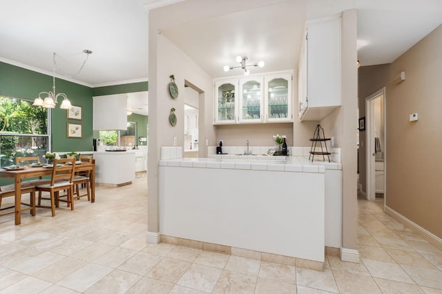 kitchen with crown molding, white cabinetry, light tile patterned floors, and a notable chandelier