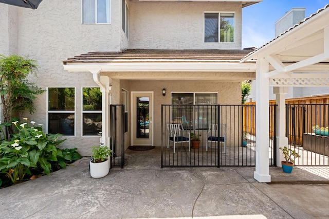 entrance to property with fence and stucco siding