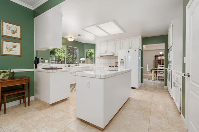 kitchen with backsplash, tile countertops, white appliances, and white cabinetry