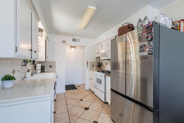 927 W Pico, Clovis, CA 93612 - kitchen featuring tile countertops, visible vents, tasteful backsplash, a sink, and white appliances