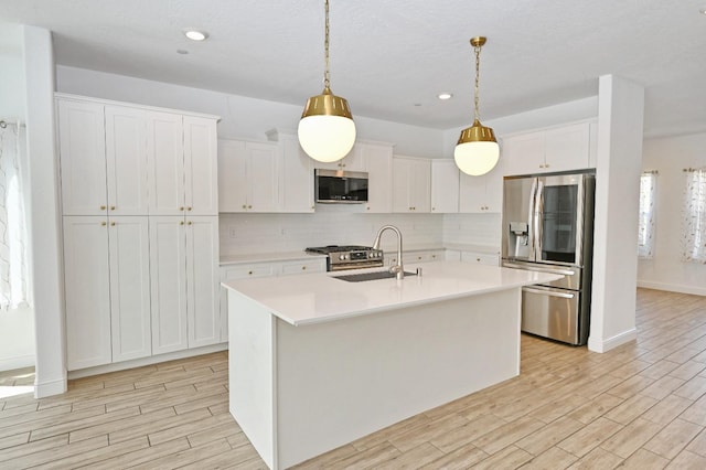 kitchen featuring a sink, stainless steel appliances, light countertops, and light wood-type flooring