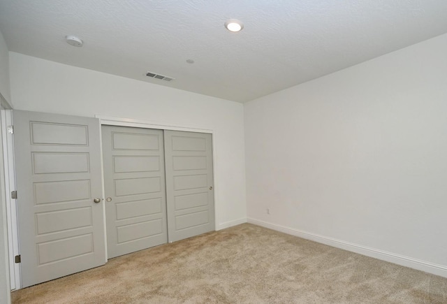 unfurnished bedroom with baseboards, carpet flooring, a closet, and visible vents