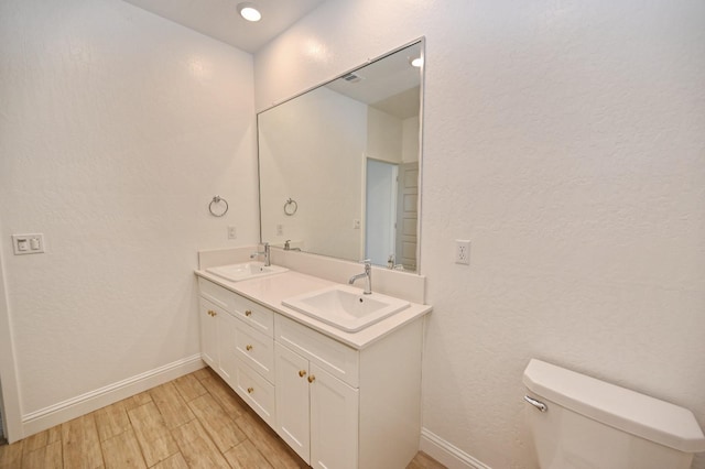 full bath featuring baseboards, toilet, a sink, and wood finished floors
