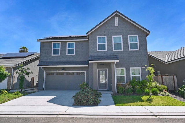traditional-style home featuring fence, a garage, solar panels, and driveway