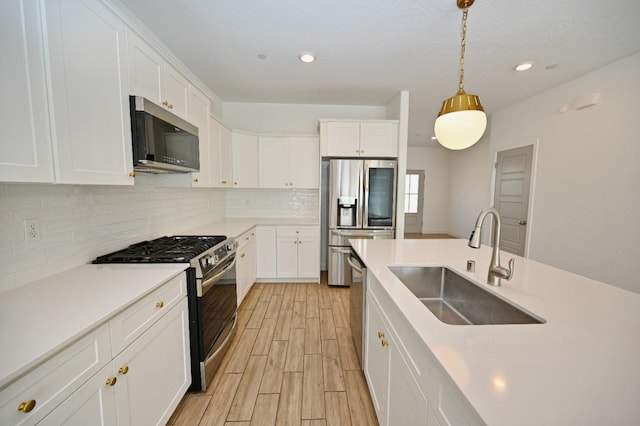 kitchen with white cabinetry, decorative backsplash, stainless steel appliances, and a sink