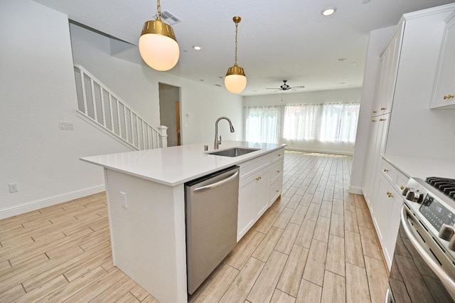 kitchen with a sink, stainless steel appliances, light wood-type flooring, a center island with sink, and light countertops