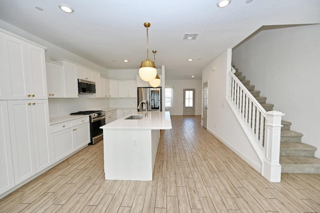 kitchen with a sink, stainless steel appliances, light wood-type flooring, visible vents, and light countertops