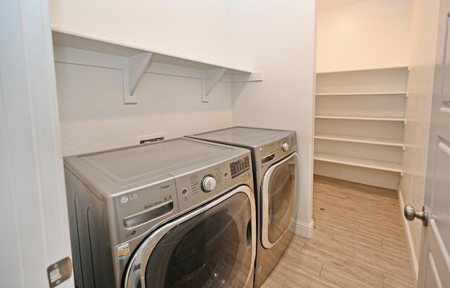 clothes washing area with washer and dryer, laundry area, and light wood-style flooring