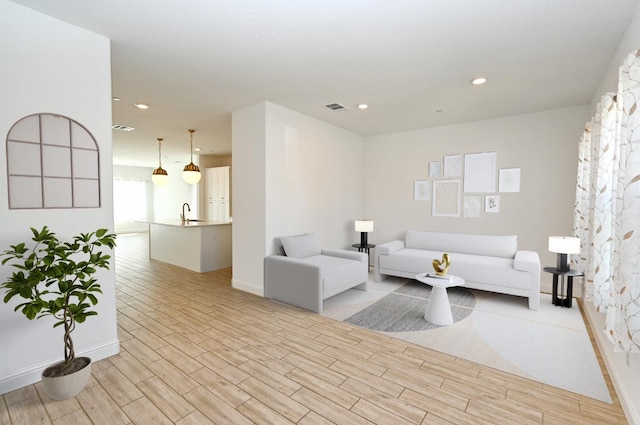 living area with baseboards, light wood-style floors, and recessed lighting