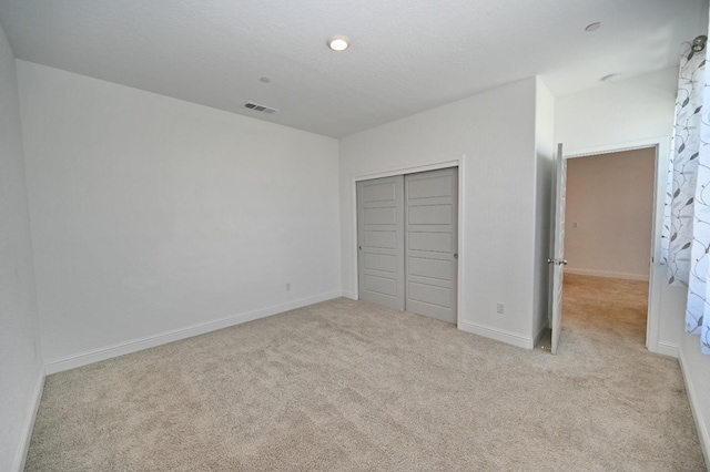 unfurnished bedroom featuring baseboards, a closet, visible vents, and carpet